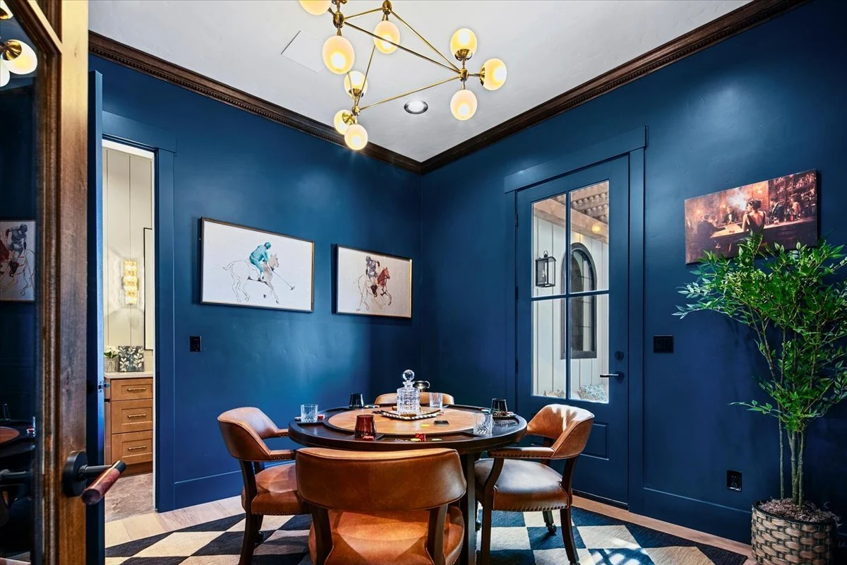 The Jane dining room with deep blue paneling, leather chairs and a sculptural light