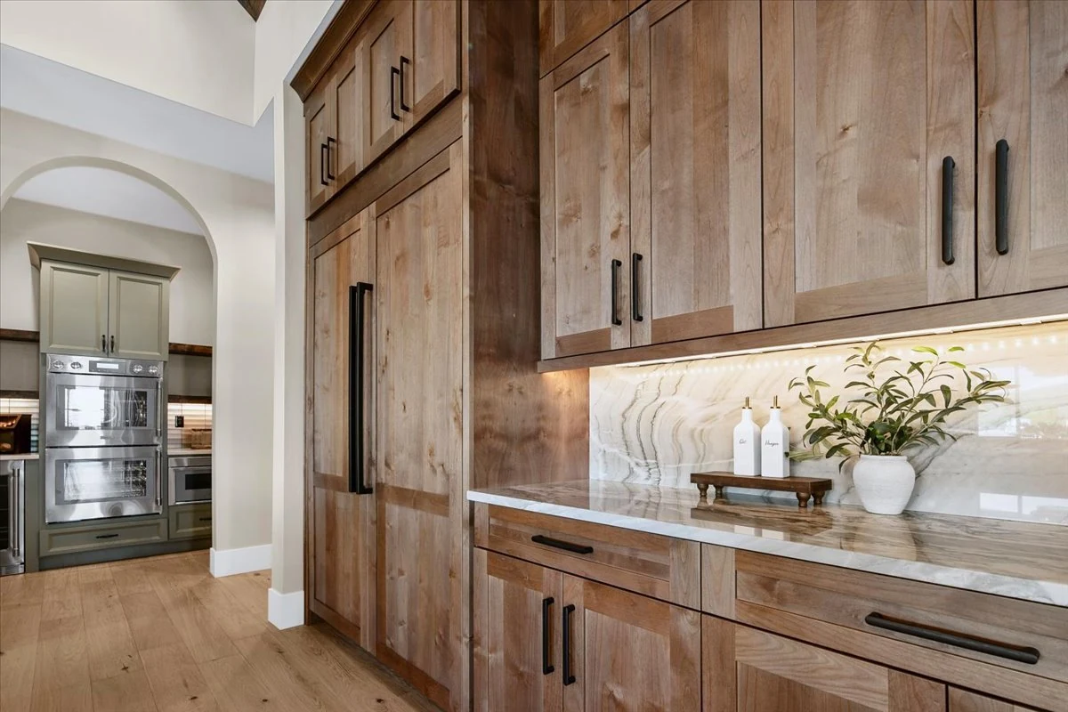 Oak cabinetry, illuminated stone backsplash and dark metal hardware in The Jane