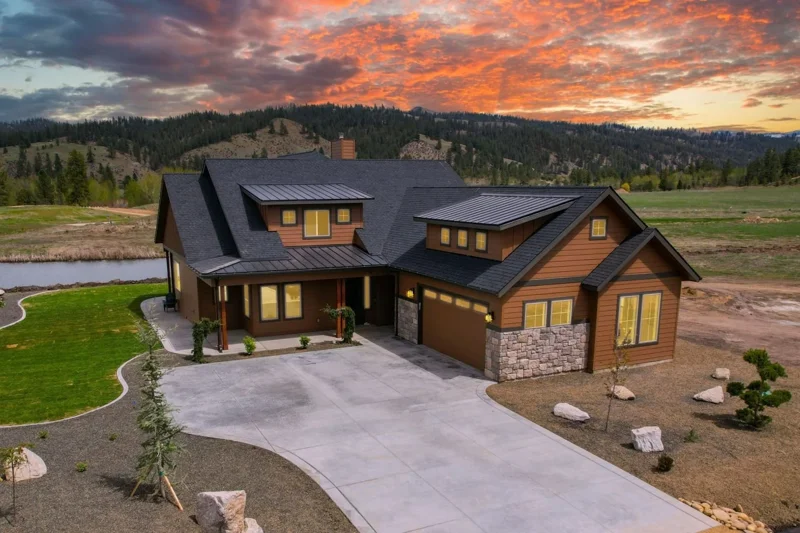 Front Exterior of the Bowen House by Bachman Custom Homes with a sunset sky and tree covered mountains in the distance