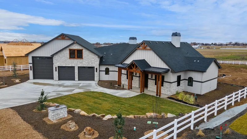 Close up of the front exterior of the Jax by Bachman Custom Homes. Light gray exterior with stone and warm toned wood details