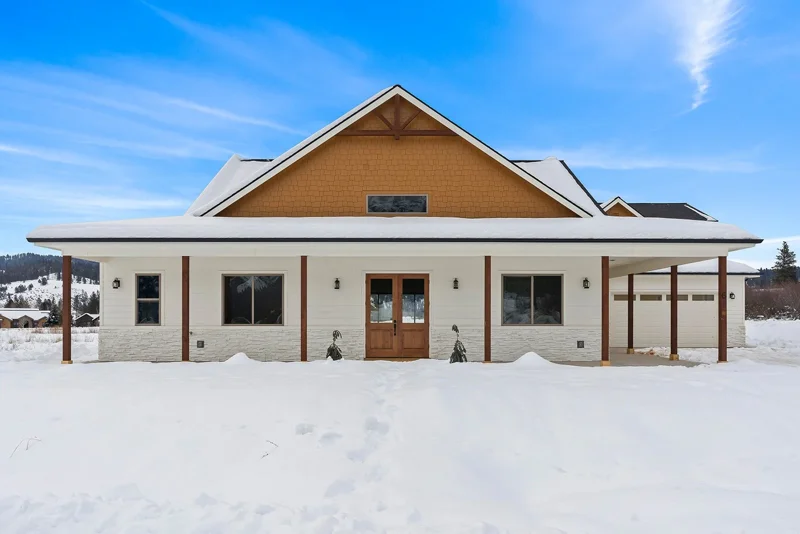 Front exterior of the Marguerite by Bachman Custom Homes. Bright white exterior with warm wood door, gable, and columns.