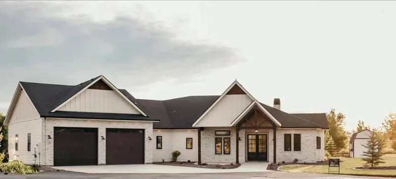 Close up of the front exterior of the Mason by Bachman Custom Homes. Light exterior with white brick and contrasting dark wood and black details and garage doors
